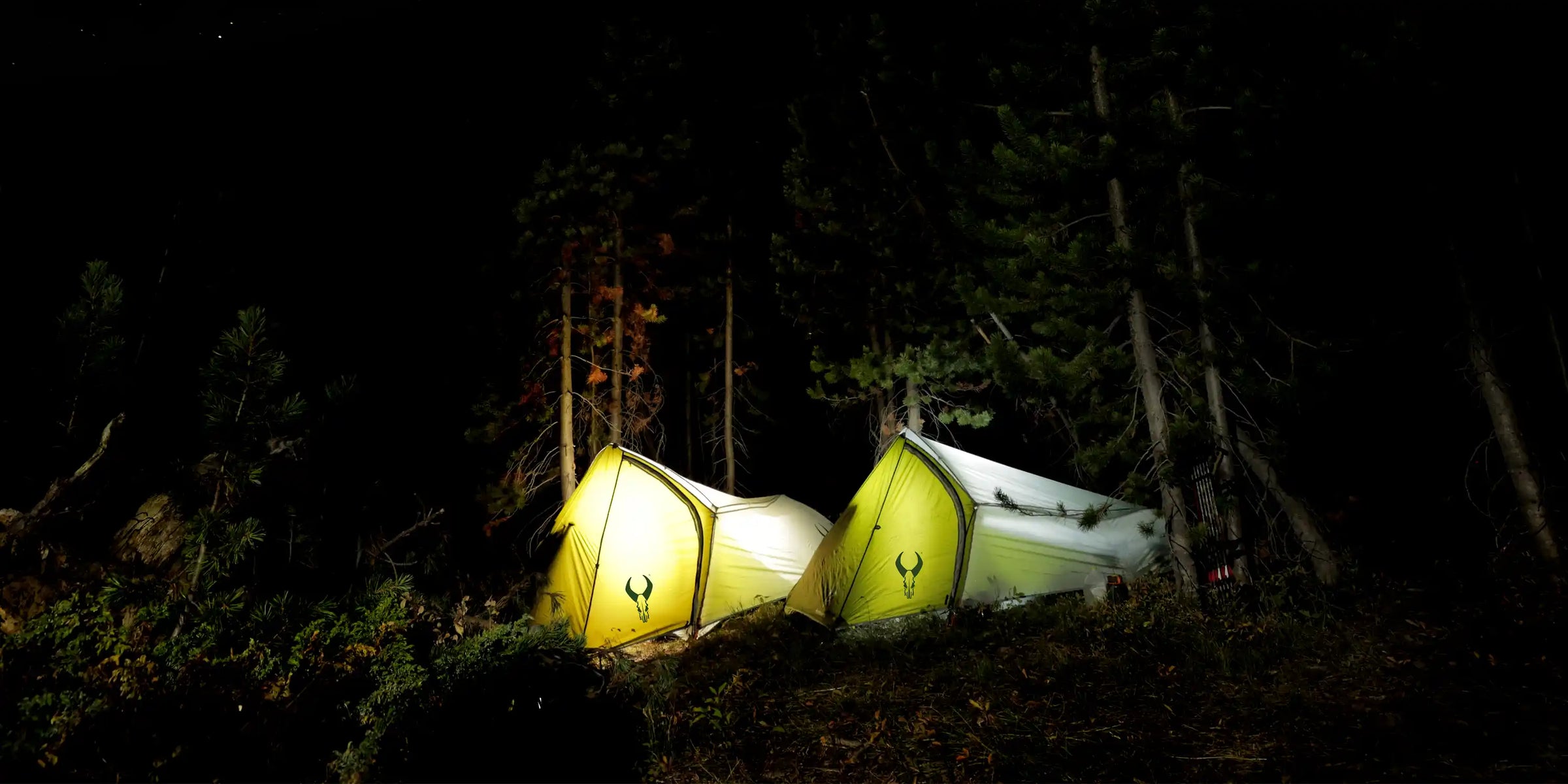 two Badlands tent in a forest at night
