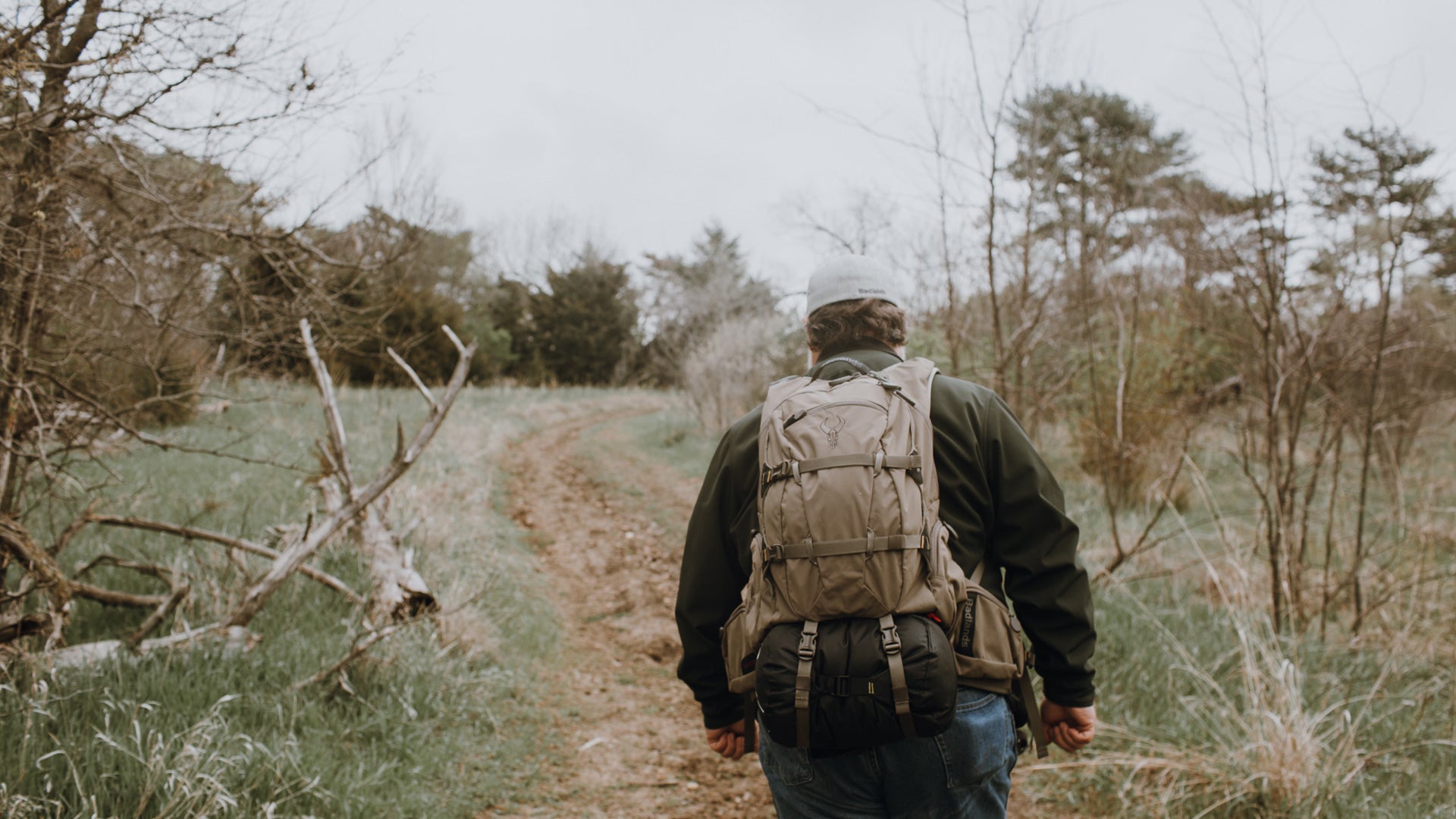 man walking down trail wearing hunting pack