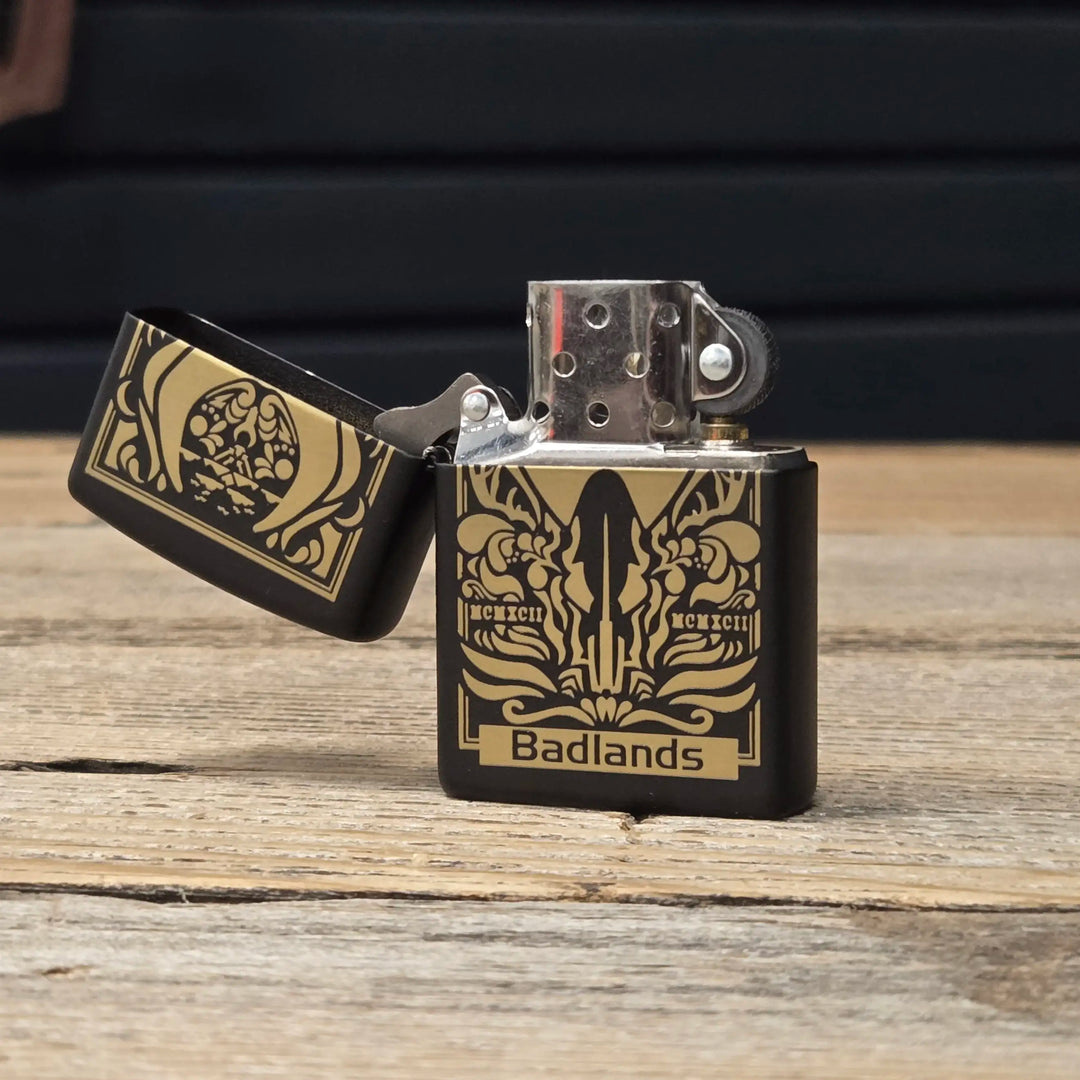 Black and gold Badlands lighter with logo skull design, open on a wooden surface.
