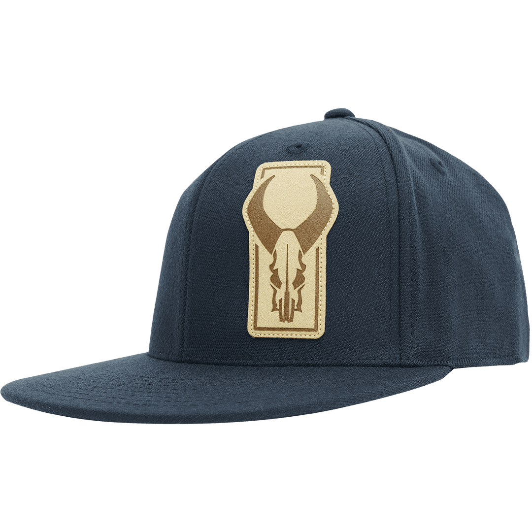 Navy flat-brim hat featuring a tan Badlands skull logo patch on the front.