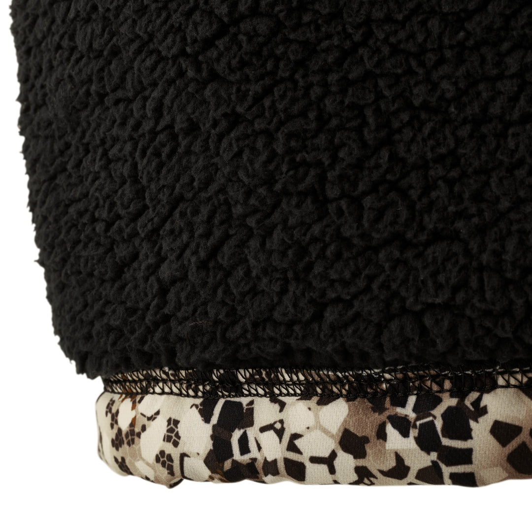 Close-up of Badlands fleece fabric with black sherpa texture and camo trim, featuring the signature skull logo pattern.