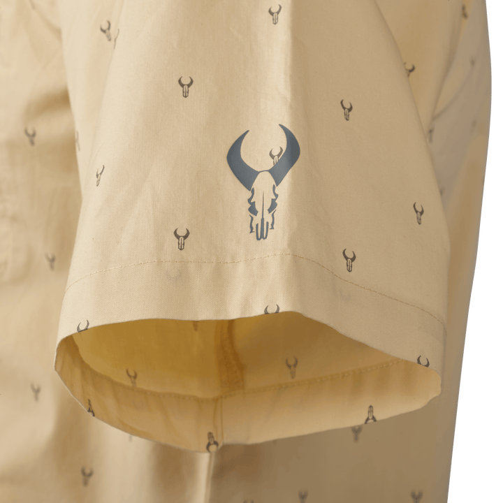 Tan shirt sleeve with repeating Badlands skull logo pattern; larger logo printed near the hem for brand emphasis.
