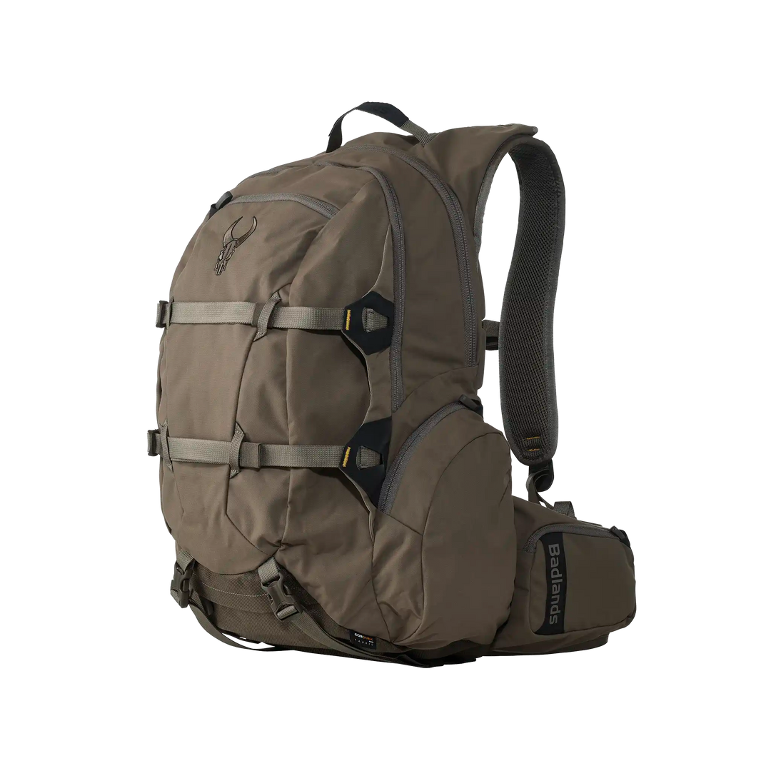 Tan Badlands backpack with skull logo, multiple compartments, padded straps, and side pocket. Designed for outdoor use.