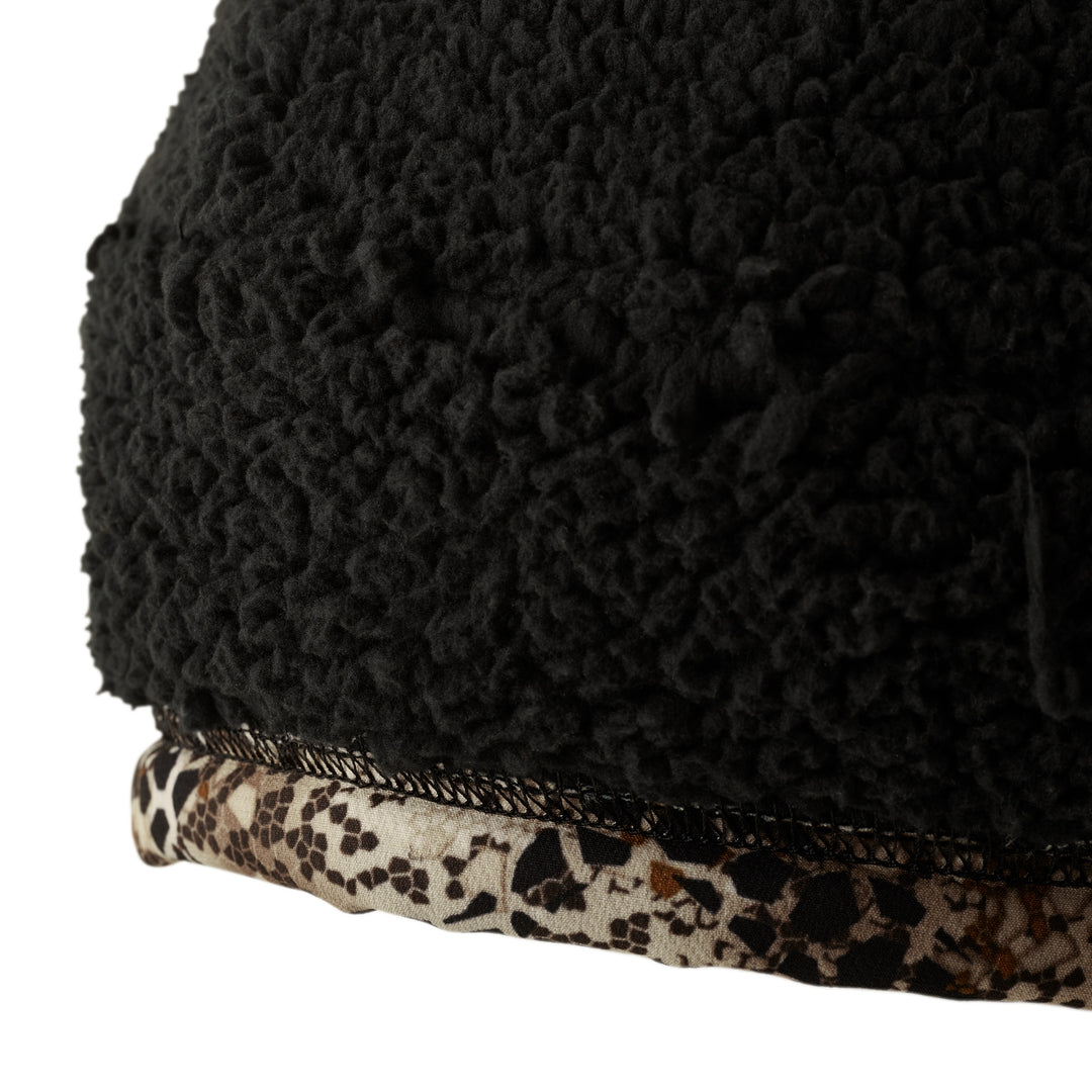 Close-up of Badlands fleece fabric with camo trim and mesh seam; textured black material above patterned edge.