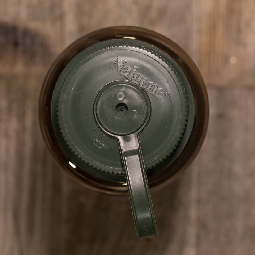 Top view of a green Nalgene bottle lid on a wood surface, featuring the Badlands skull logo.