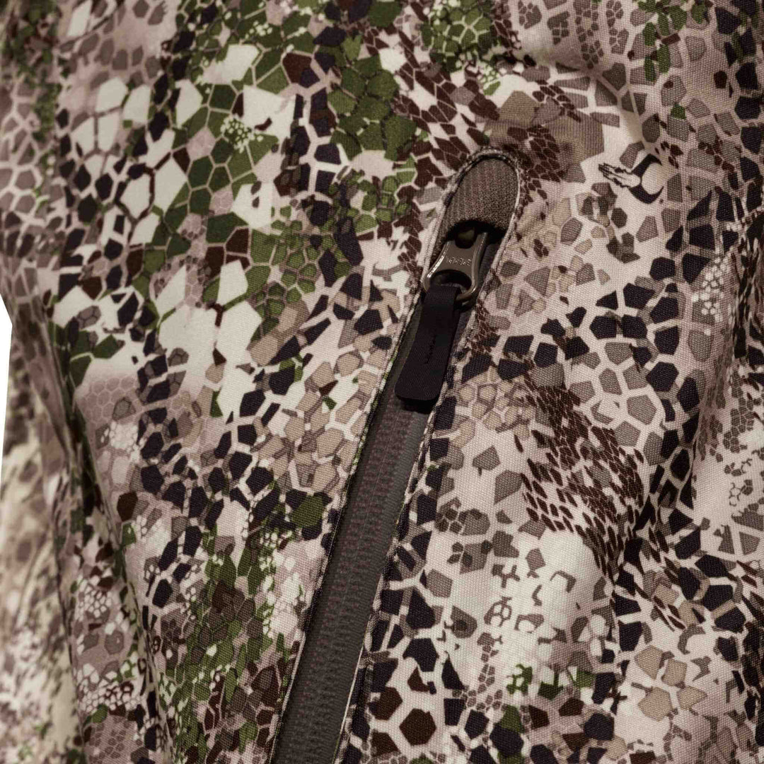 Close-up of Badlands camo fabric with zipper and subtle Badlands skull logo for outdoor gear.