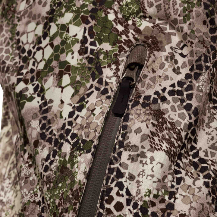 Close-up of Badlands camo fabric with zipper and subtle Badlands skull logo for outdoor gear.