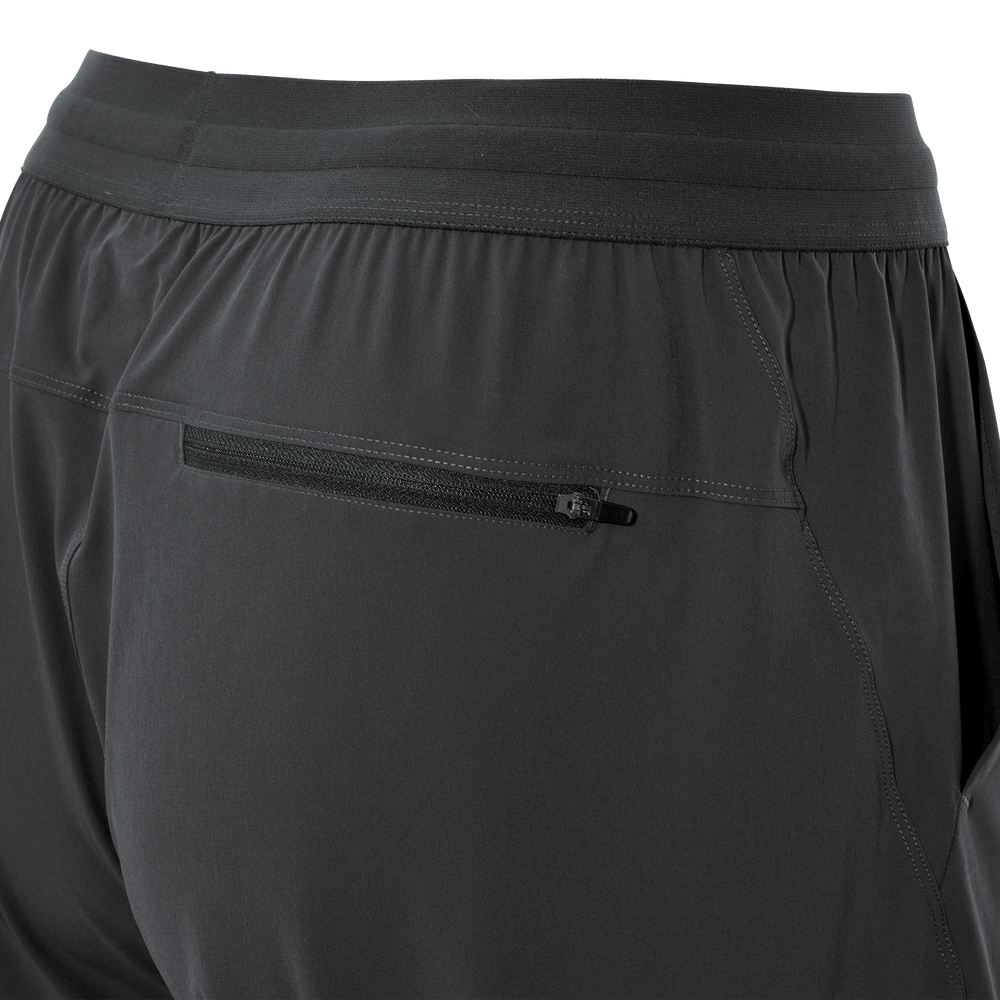 Close-up of Badlands shorts' back zip pocket with subtle skull logo on the zipper pull, dark fabric, elastic waistband.