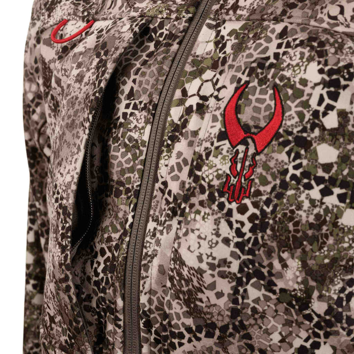 Close-up of Badlands camo jacket with red skull logo and zipper, showing textured hunting pattern.