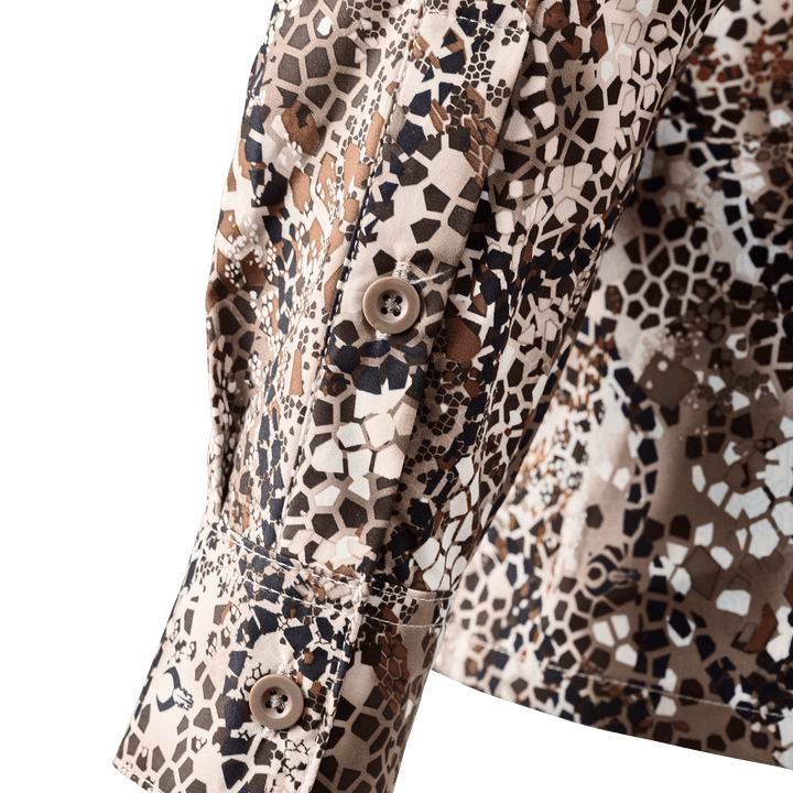 Close-up of a Badlands camo shirt cuff with buttons; subtle Badlands skull logo in the pattern.