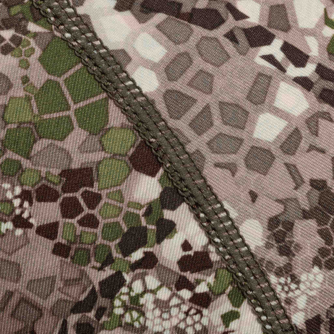 Close-up of Badlands camo fabric with detailed stitching and geometric pattern in green, brown, and tan.