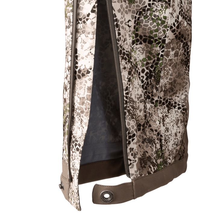 Close-up of Badlands camo pant leg with zipper and snap closure; Badlands skull logo on snap button.