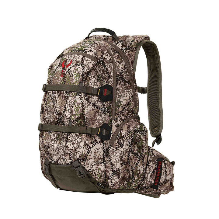 Badlands camo hunting backpack with red skull logo, padded straps, and multiple zippered compartments for gear organization.