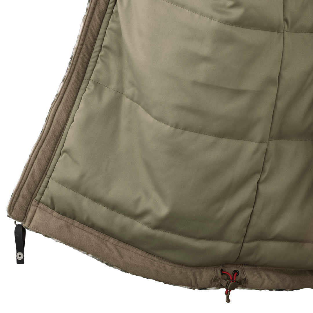 Close-up of a Badlands jacket hem with logo skull drawcord and zipper, showing quilted olive fabric and brown trim.
