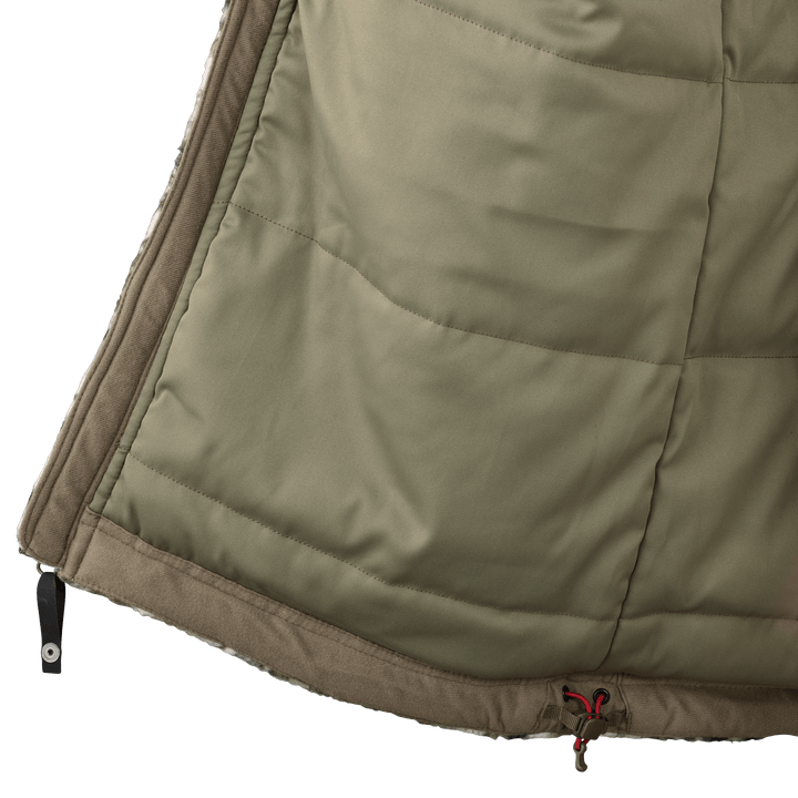 Close-up of a Badlands jacket hem with logo skull drawcord and zipper, showing quilted olive fabric and brown trim.