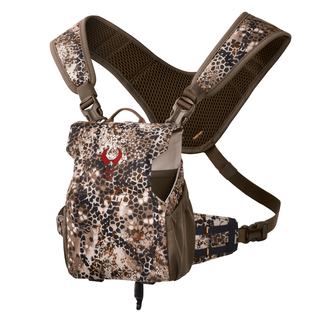 Badlands camo binocular harness with red skull logo, padded straps, and mesh backing for comfort and support.