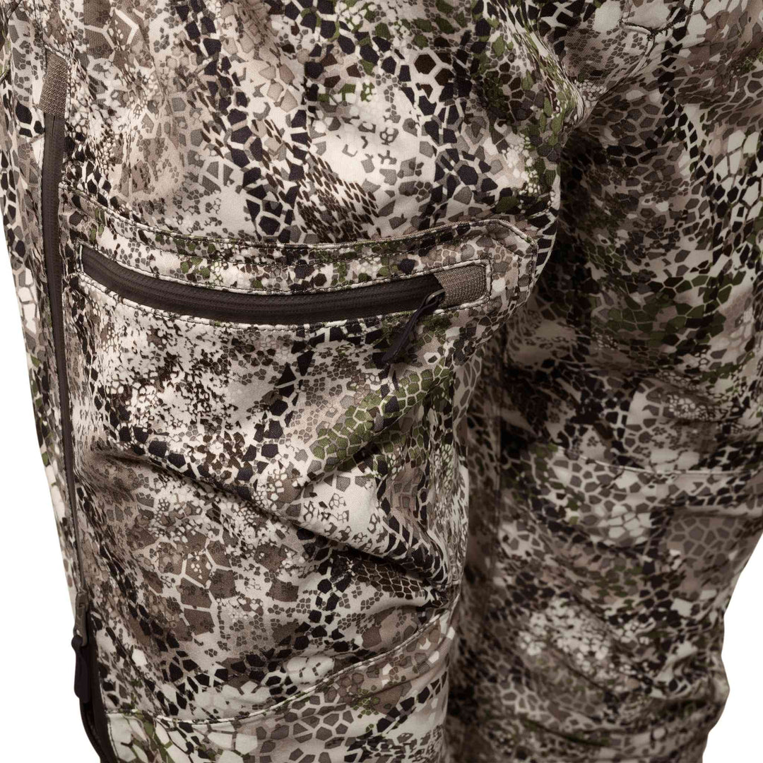 Close-up of Badlands camo hunting pants with zippered pocket and subtle Badlands skull logo on the fabric.