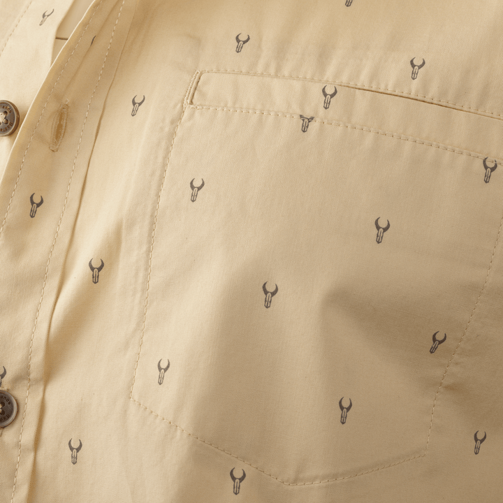 Close-up of tan shirt pocket with small, repeated Badlands skull logos in a subtle pattern.