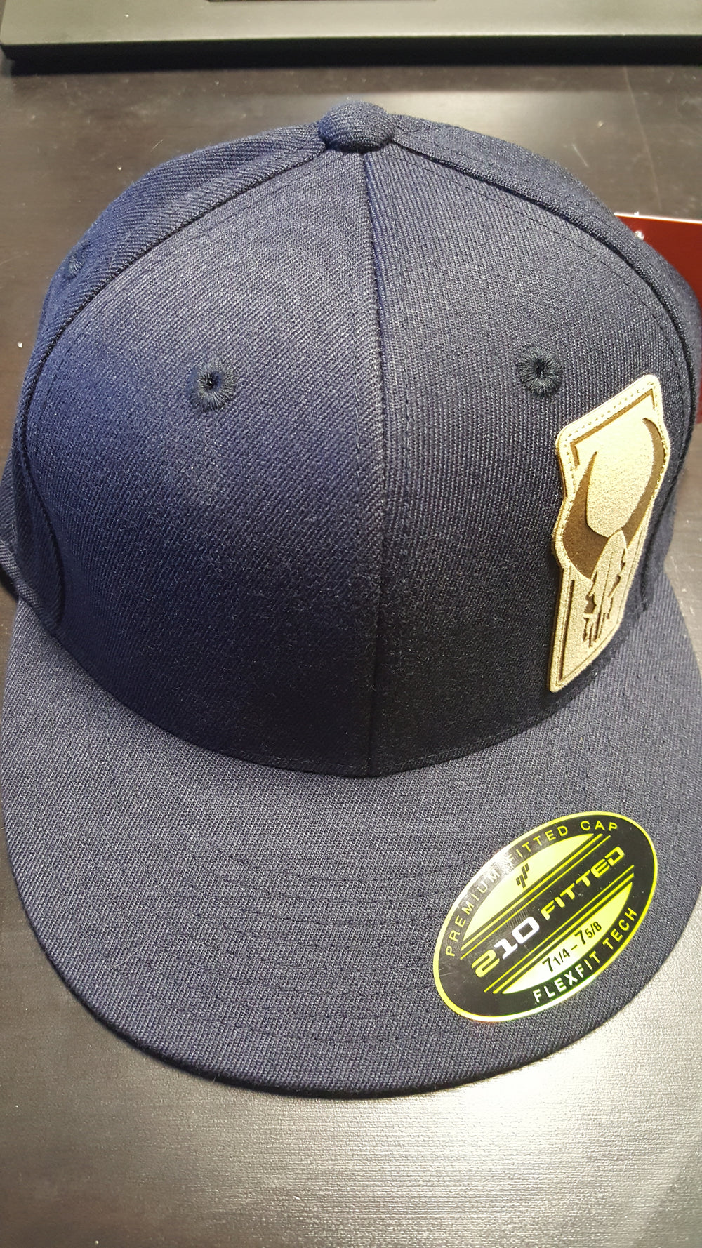 Navy Badlands cap with tan Badlands skull logo patch on front, Flexfit 210 Fitted sticker on brim.