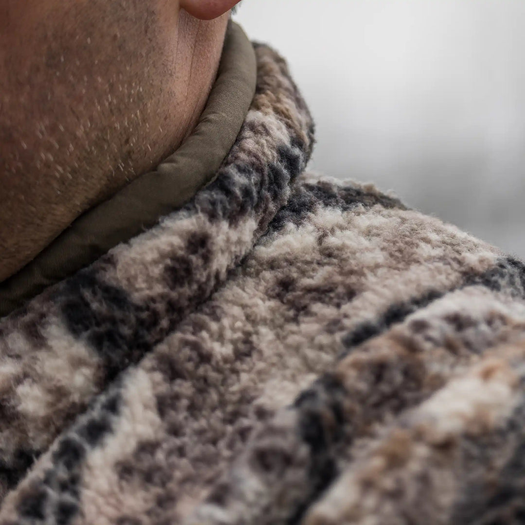 Close-up of a person wearing a soft, camo-patterned Badlands fleece jacket, showing texture and warmth.