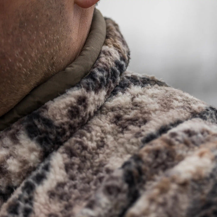 Close-up of a person wearing a soft, camo-patterned Badlands fleece jacket, showing texture and warmth.