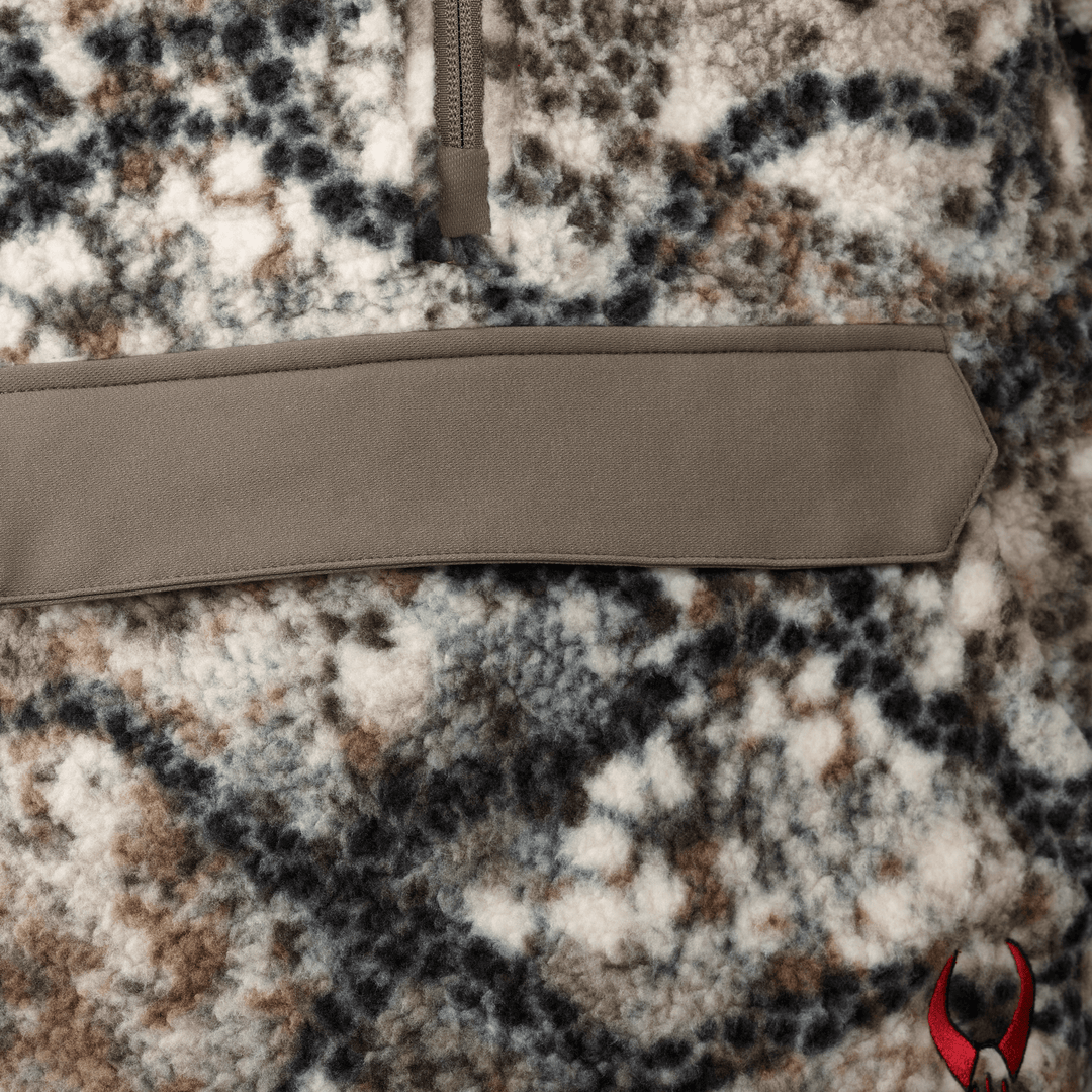 Close-up of Badlands camo fleece with a tan pocket and red Badlands skull logo in the lower right corner.