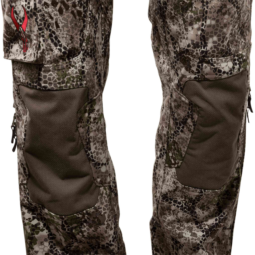 Close-up of Badlands camo hunting pants with reinforced knee panels and red Badlands skull logo on the left pocket.