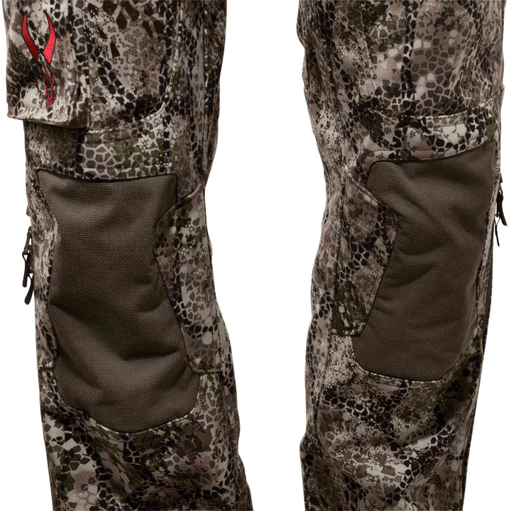 Close-up of Badlands camo hunting pants with reinforced knee panels and red Badlands skull logo on the left pocket.