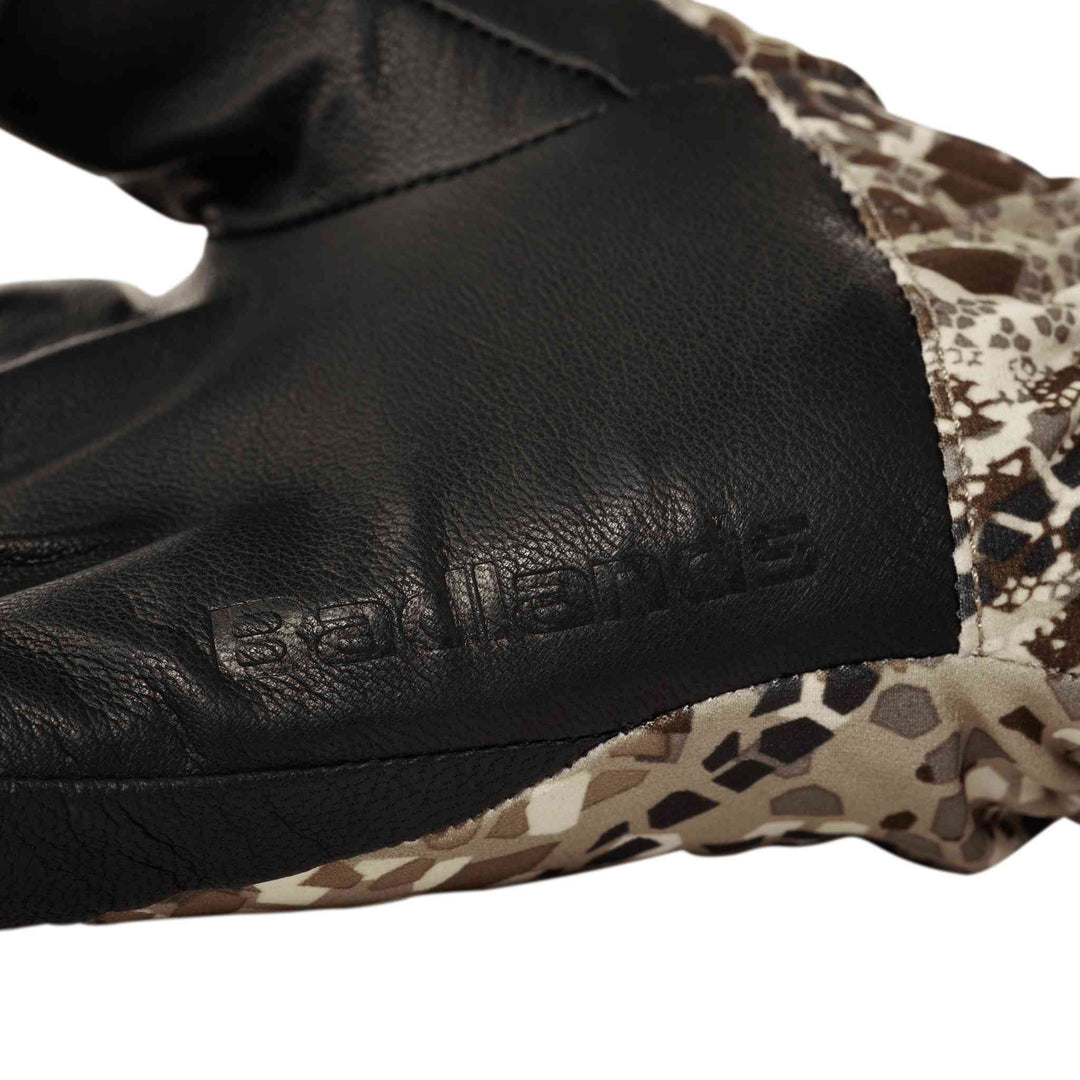 Close-up of a Badlands glove with embossed logo, featuring black leather and camo fabric for outdoor use.