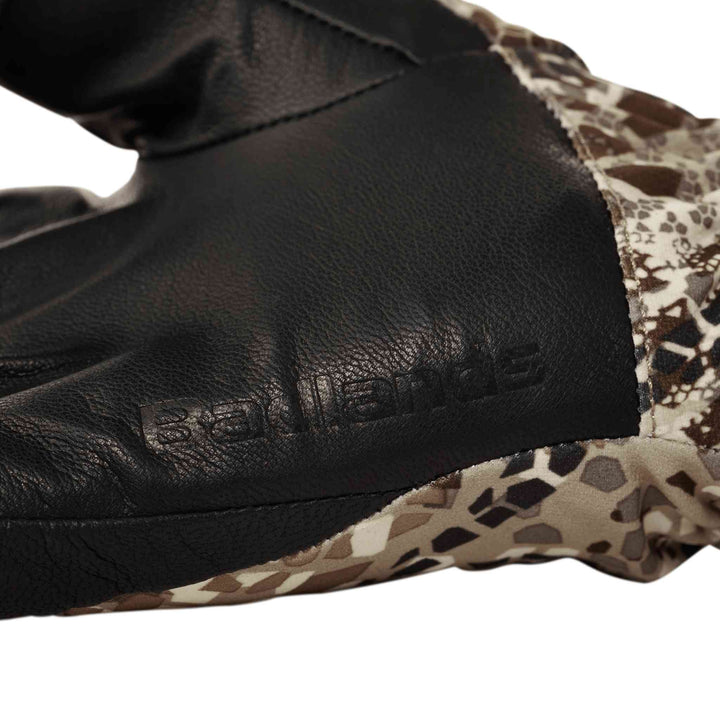 Close-up of a Badlands glove with embossed logo, featuring black leather and camo fabric for outdoor use.