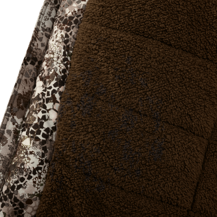 Close-up of Badlands fleece fabric with camo pattern and subtle skull logo for outdoor gear.