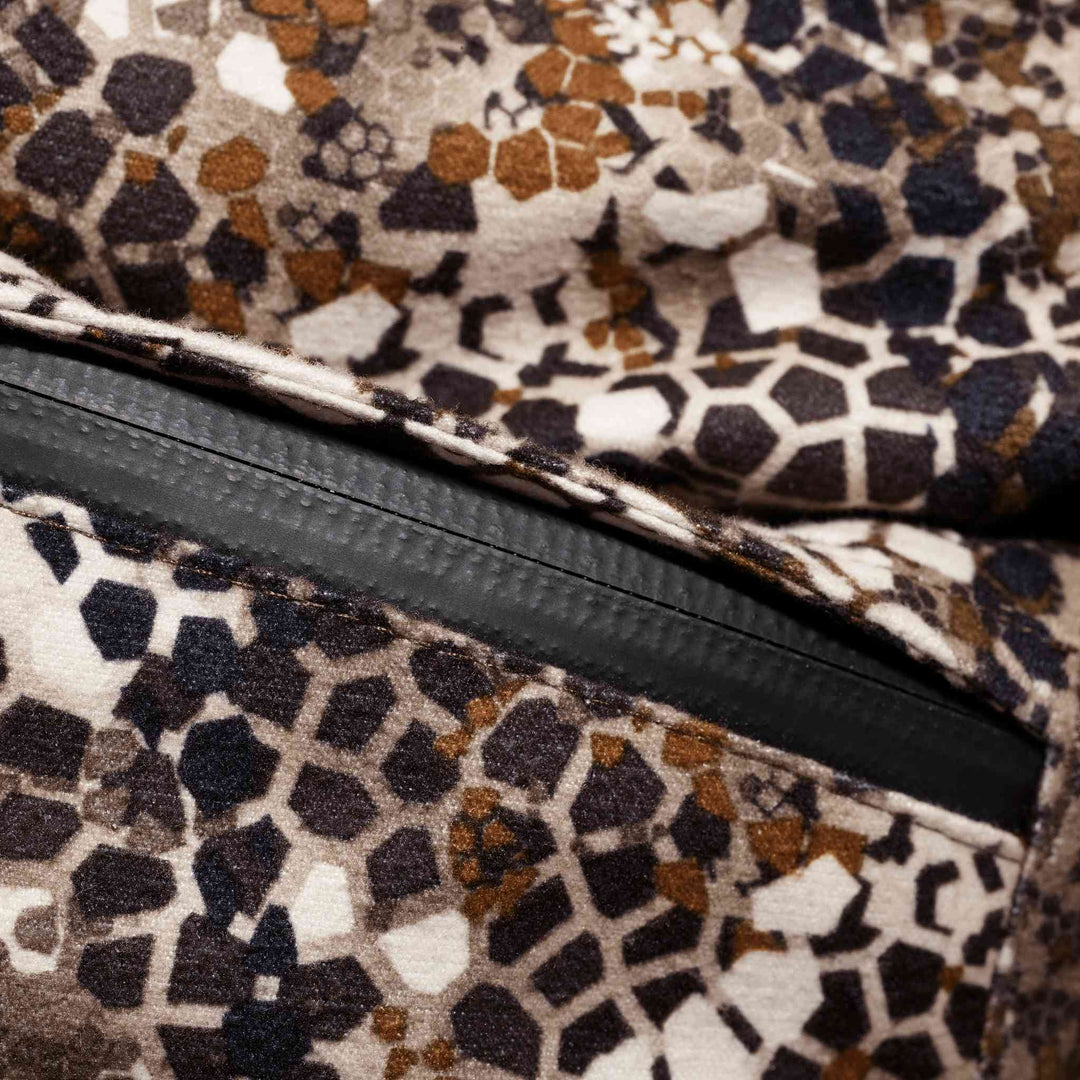 Close-up of Badlands camo fabric with a zipper, featuring geometric patterns in brown, tan, and black.