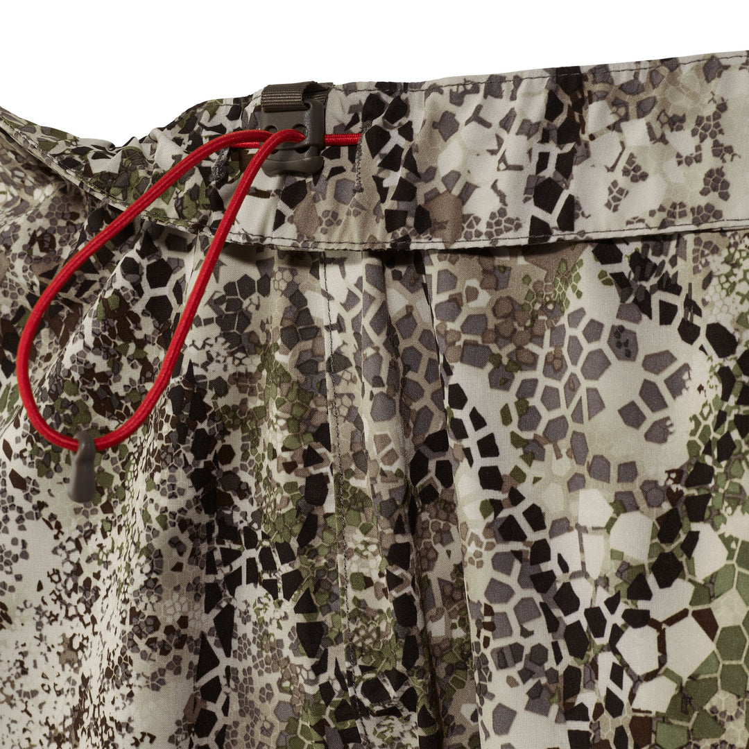 Badlands camo fabric close-up with red drawstring and skull logo on waistband, designed for outdoor and hunting use.