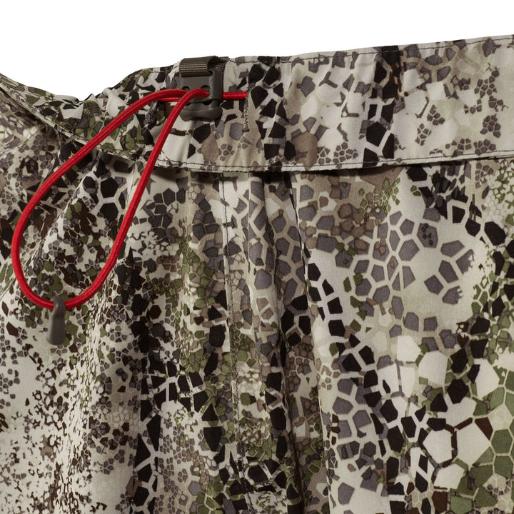 Badlands camo fabric close-up with red drawstring and skull logo on waistband, designed for outdoor and hunting use.
