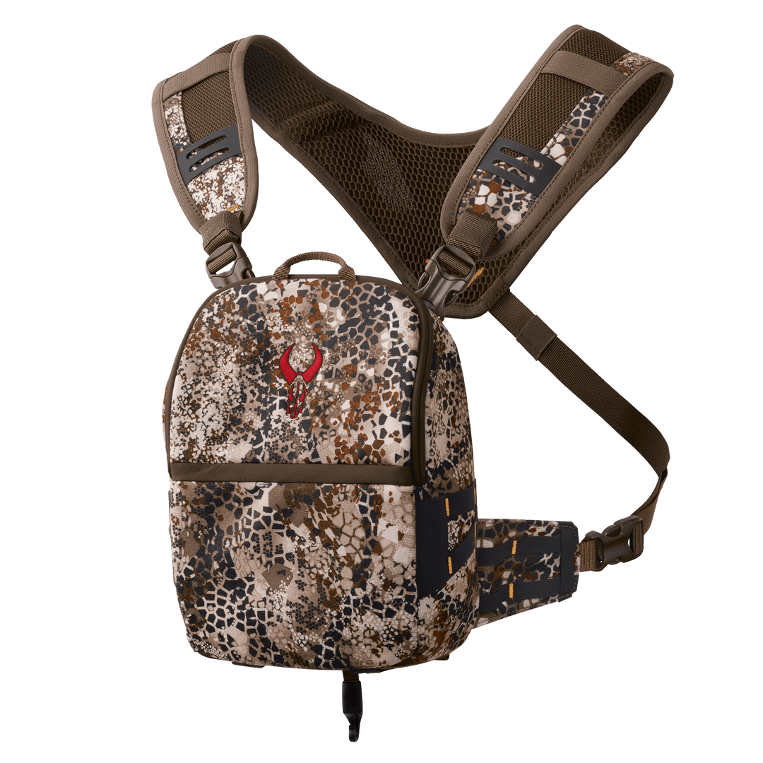Badlands camo chest pack with red skull logo, adjustable straps, and mesh back panel for outdoor gear organization.