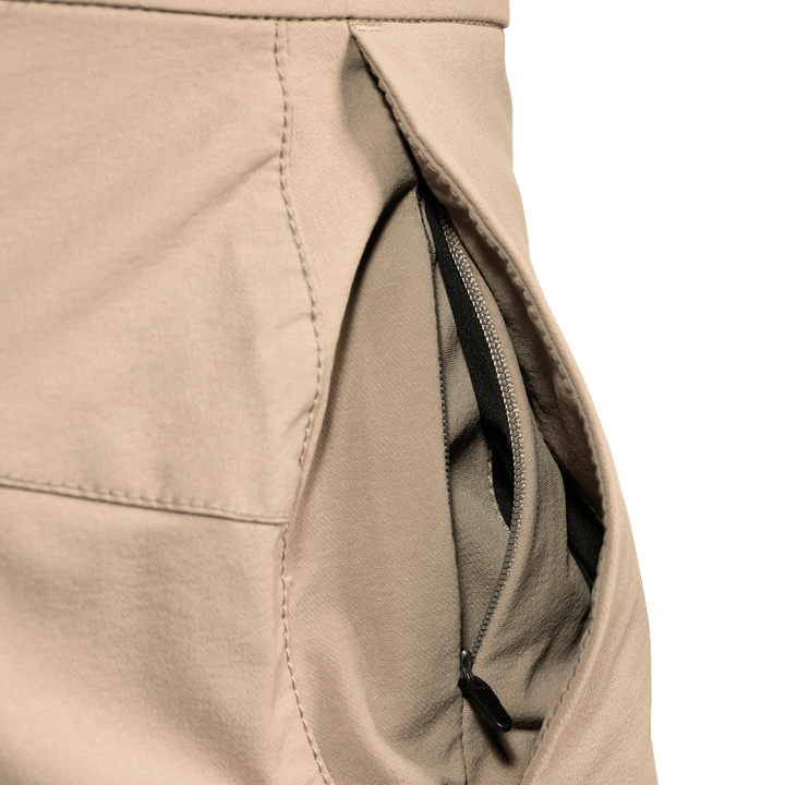 Close-up of a tan Badlands pant pocket with an inner zippered compartment for secure storage. No visible logo.