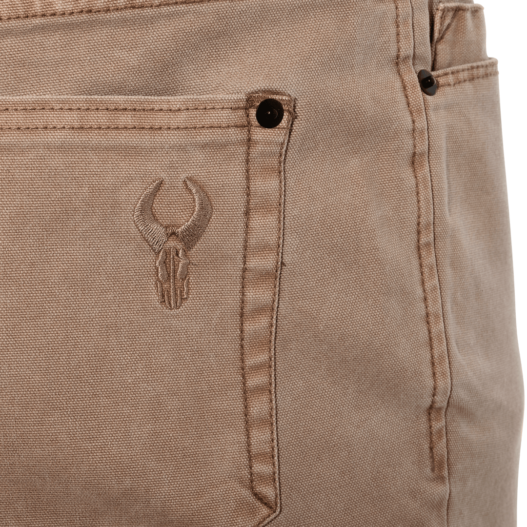 Close-up of tan Badlands pants pocket with embroidered skull logo, designed for outdoor durability and easy identification.