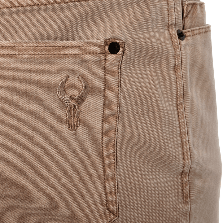 Close-up of tan Badlands pants pocket with embroidered skull logo, designed for outdoor durability and easy identification.