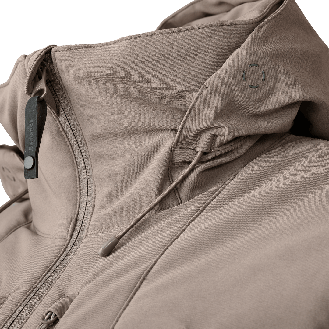 Close-up of a tan Badlands jacket with logo skull, zipper, and adjustable hood drawstring.