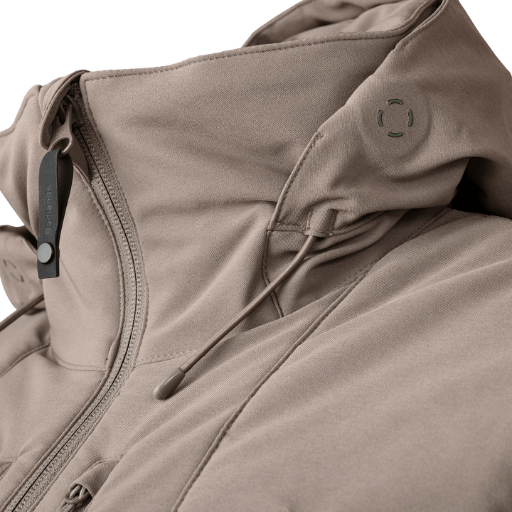 Close-up of a tan Badlands jacket with logo skull, zipper, and adjustable hood drawstring.