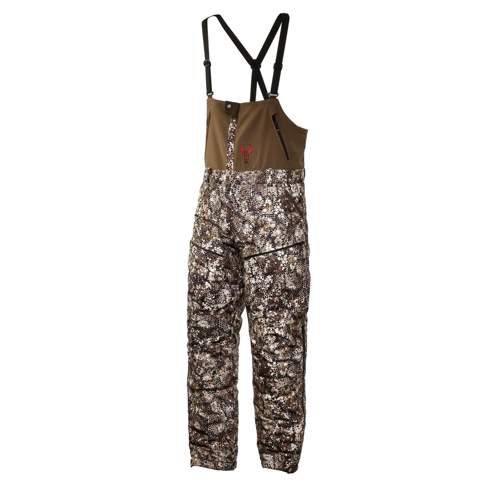 Badlands camo hunting bib with suspenders and red skull logo on chest; features zippered pockets and durable fabric.