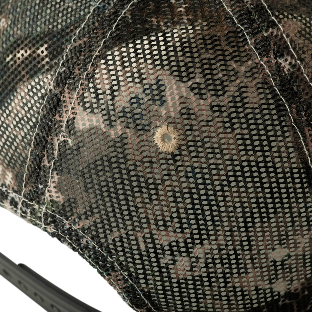 Close-up of mesh camo Badlands cap with stitched skull logo on top; adjustable strap visible bottom left.