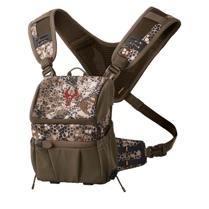Badlands camo binocular harness with red skull logo, padded straps, and multiple pockets for outdoor gear.