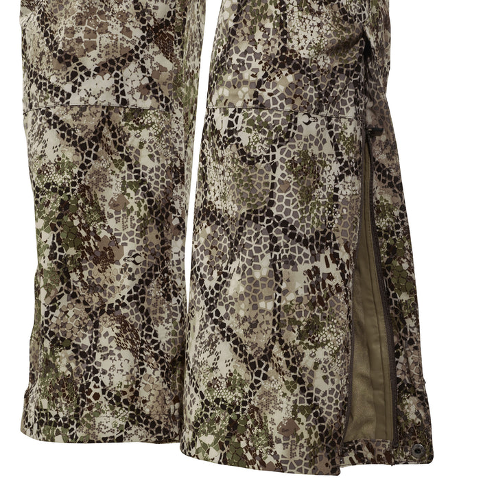 Close-up of Badlands camo rain pants with side zipper open, showing waterproof material and detailed camouflage pattern.