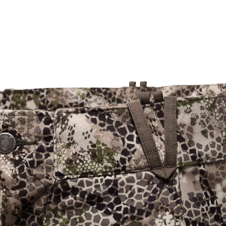 Close-up of Badlands camo pants waistband with belt loops and skull logo button, showing detailed pattern and stitching.