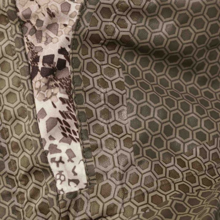 Close-up of Badlands camo fabric with hexagonal pattern and subtle skull logo, designed for outdoor gear.