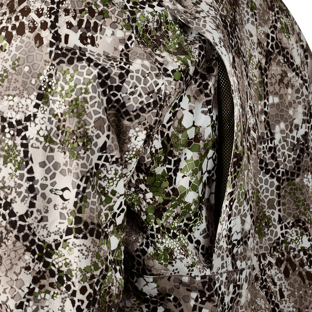 Close-up of Badlands camo fabric with a zippered vent; features hexagonal pattern and subtle Badlands skull logo.